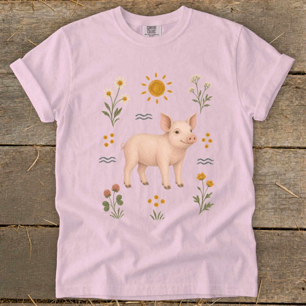 Pink t-shirt with a drawing of a pig, sun, waves, and flowers.
