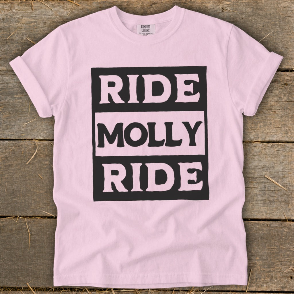 Light pink crewneck t-shirt with rolled sleeves laid flat on wood, featuring the text "RIDE MOLLY RIDE".
