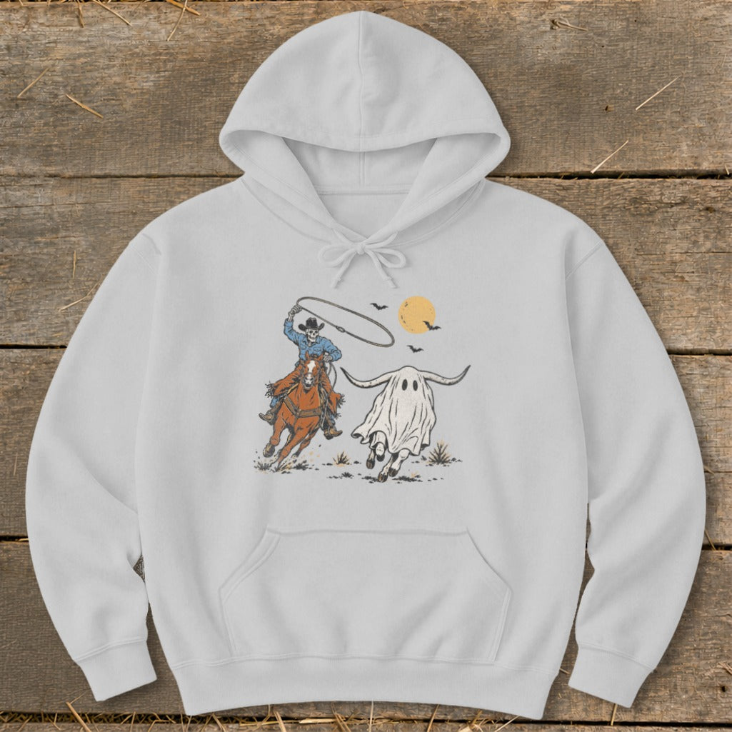 Skeleton cowboy on horse chasing a white ghost with horns under a yellow moon.