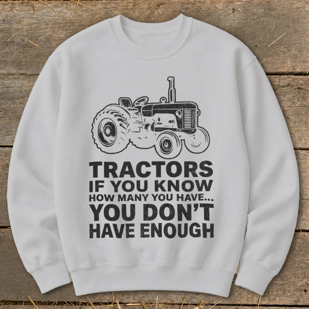 White sweatshirt with a vintage tractor graphic and text "TRACTORS IF YOU KNOW HOW MANY YOU HAVE... YOU DON'T HAVE ENOUGH".