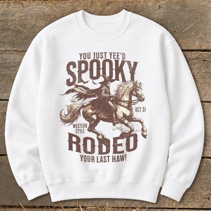 White sweatshirt with spooky cowboy riding a horse and "Spooky Rodeo" text.