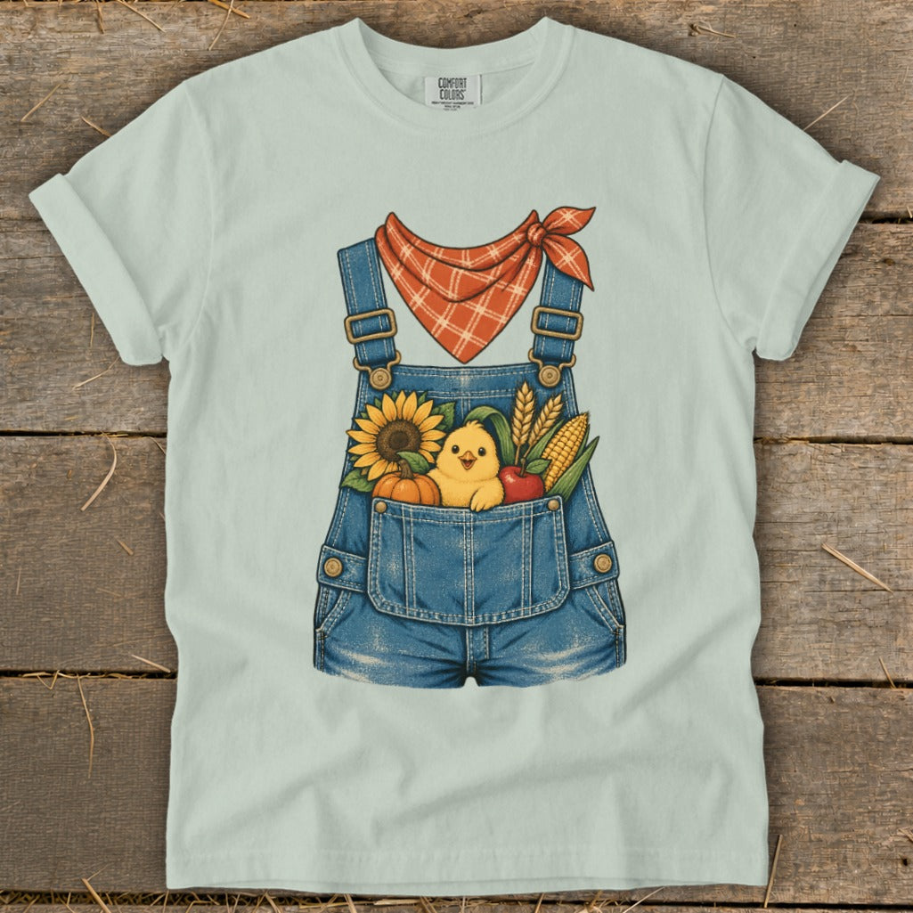 Light blue t-shirt featuring cartoon overalls with a chick and fall harvest elements.