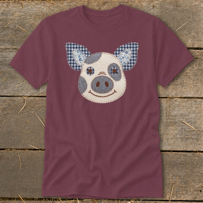 Burgundy t-shirt with a stitched pig face applique featuring plaid ears.