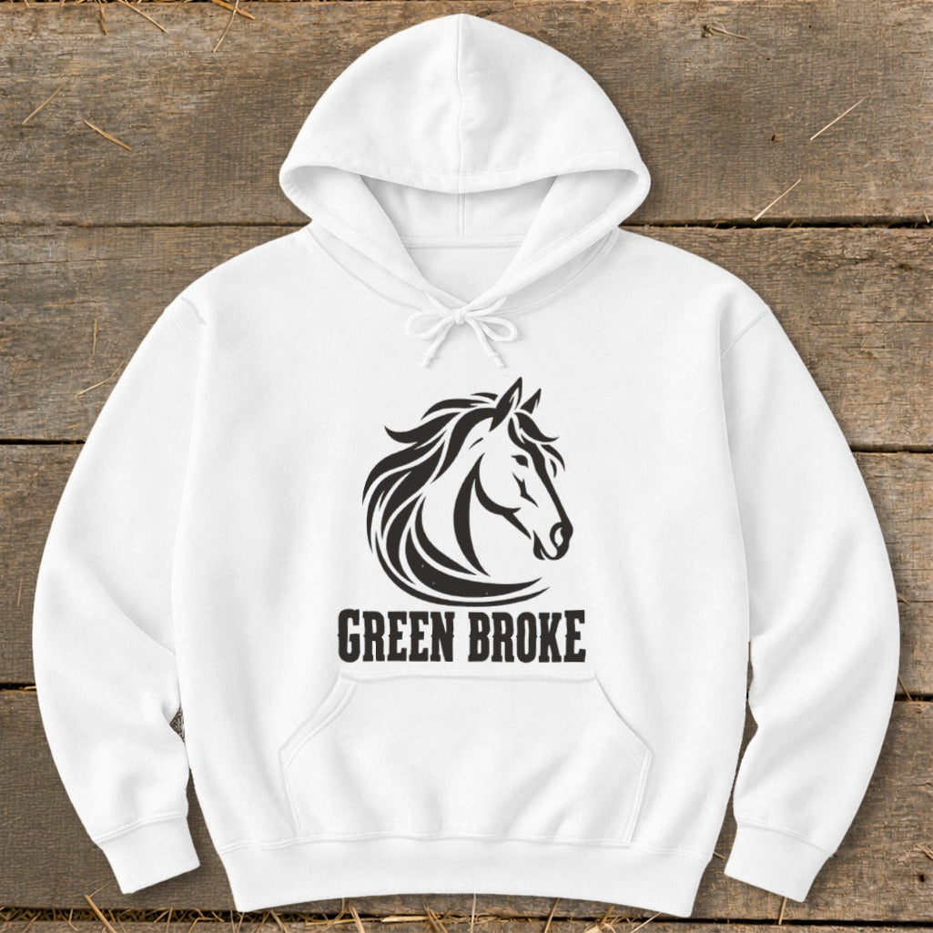 White hoodie featuring a black graphic of a horse head and the text "GREEN BROKE" resting on a wooden surface.