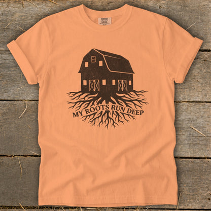 Peach t-shirt with barn and roots graphic, reads "MY ROOTS RUN DEEP".