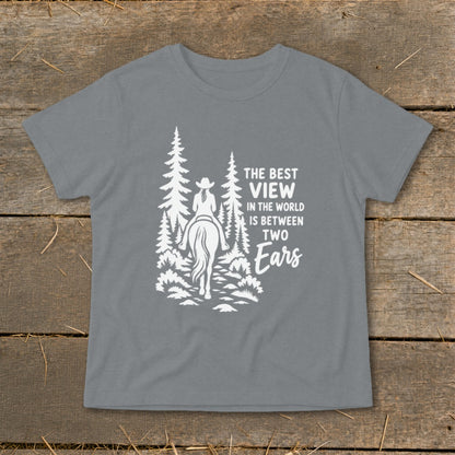 A gray short-sleeved t-shirt featuring a white graphic of a horseback rider in a forest and text that reads, "The best view in the world is between two ears."