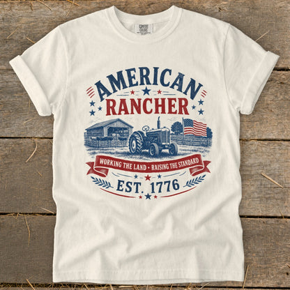 White t-shirt with "American Rancher Est. 1776" graphic including tractor, barn, and flag.