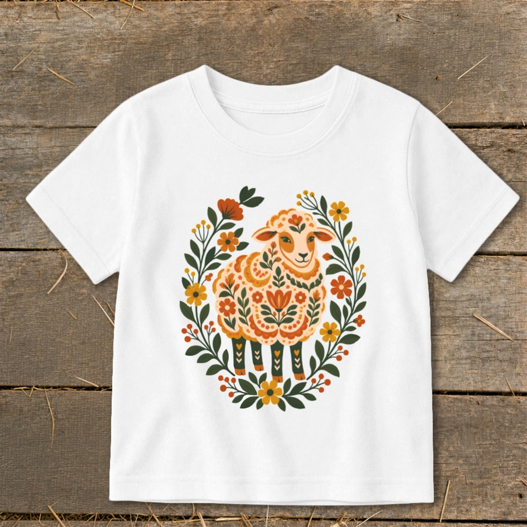 White t-shirt with a sheep surrounded by a floral wreath design.