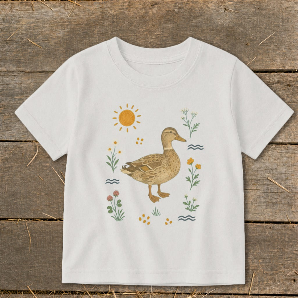 White t-shirt with a brown duck illustration surrounded by sun, flowers, and water elements.