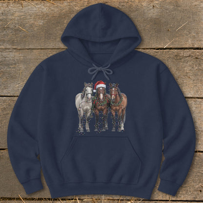 Three horses, one with a Santa hat, are decorated with Christmas lights.