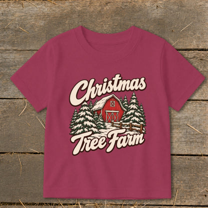 Pink t-shirt with "Christmas Tree Farm" graphic featuring a red barn and snow-covered trees.