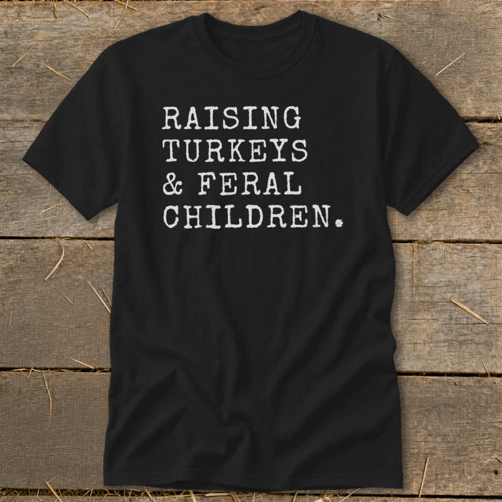 Black t-shirt with white text that reads "RAISING TURKEYS & FERAL CHILDREN."