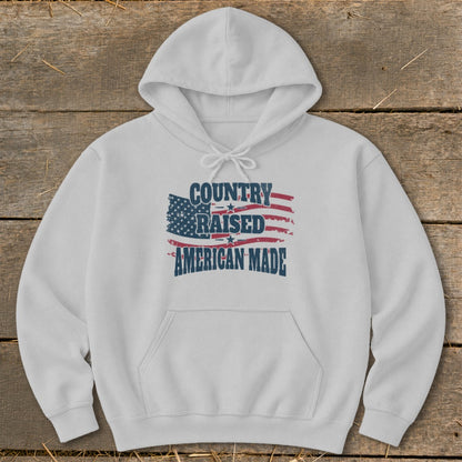 White hoodie with "Country Raised American Made" text over a distressed American flag graphic.