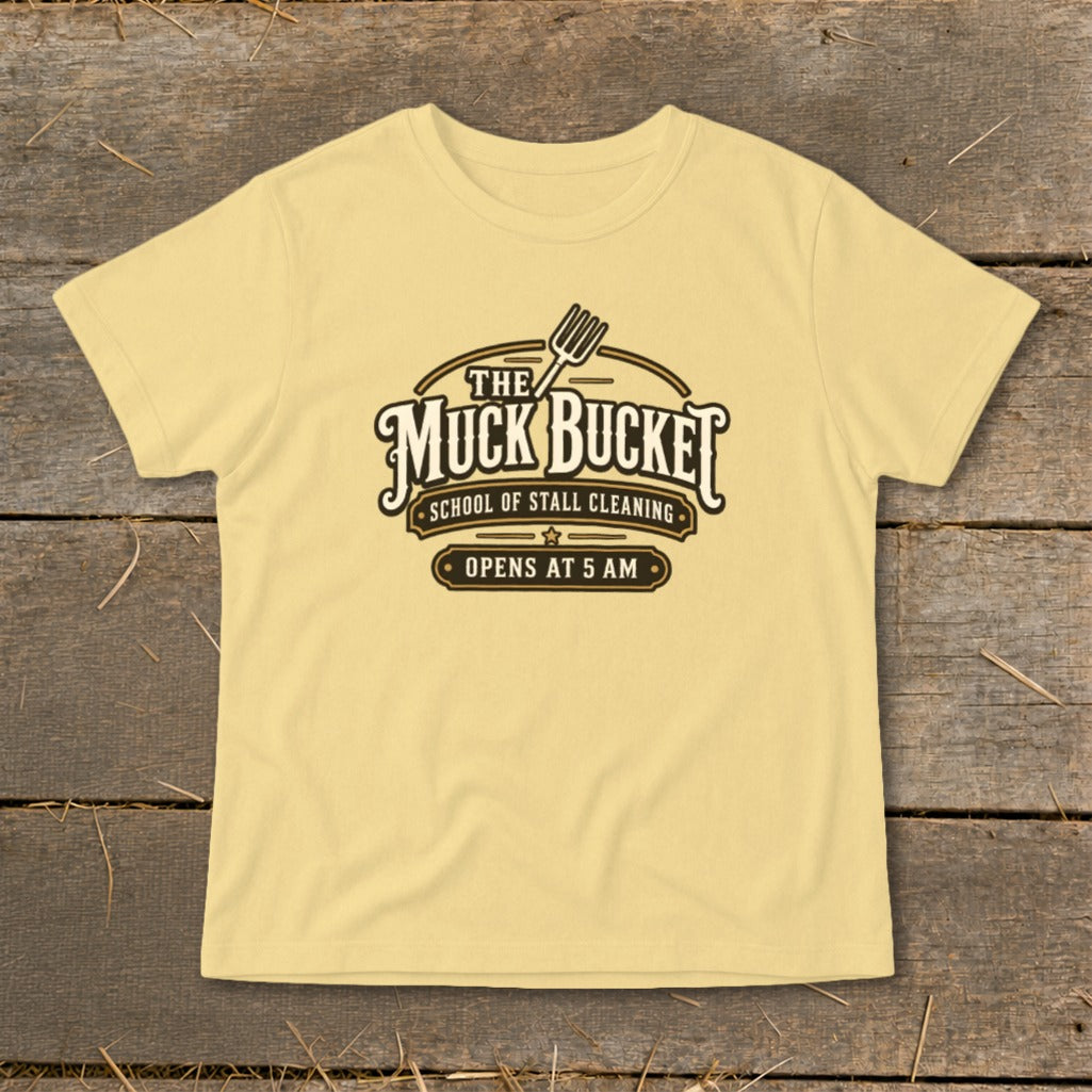 Yellow t-shirt with "The Muck Bucket School of Stall Cleaning Opens At 5 AM" logo.