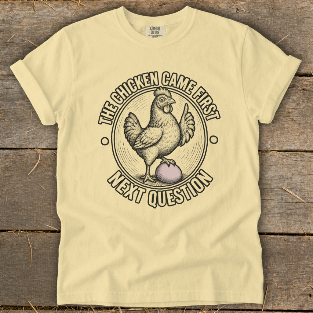 Yellow t-shirt with chicken and egg graphic and text "The chicken came first, next question".