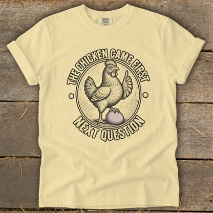 Yellow t-shirt with chicken and egg graphic and text "The chicken came first, next question".