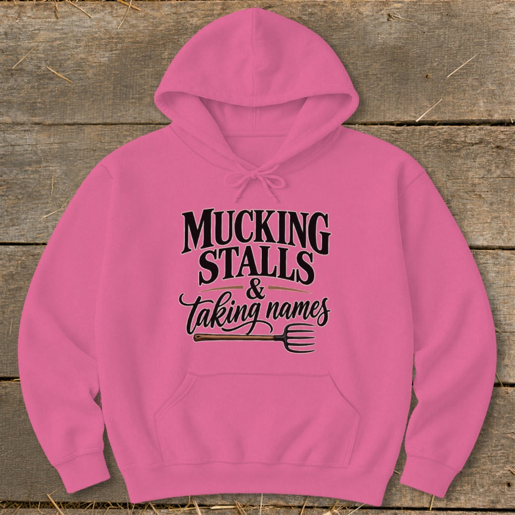 Pink hoodie with "Mucking Stalls & Taking Names" text and pitchfork graphic.