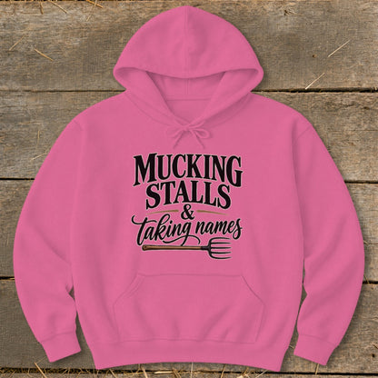 Pink hoodie with "Mucking Stalls & Taking Names" text and pitchfork graphic.