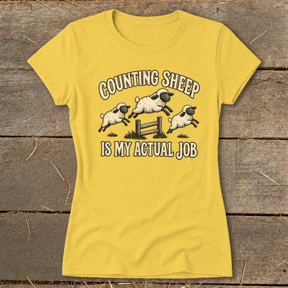 Yellow t-shirt with graphic "Counting Sheep Is My Actual Job" and three sheep jumping fence.