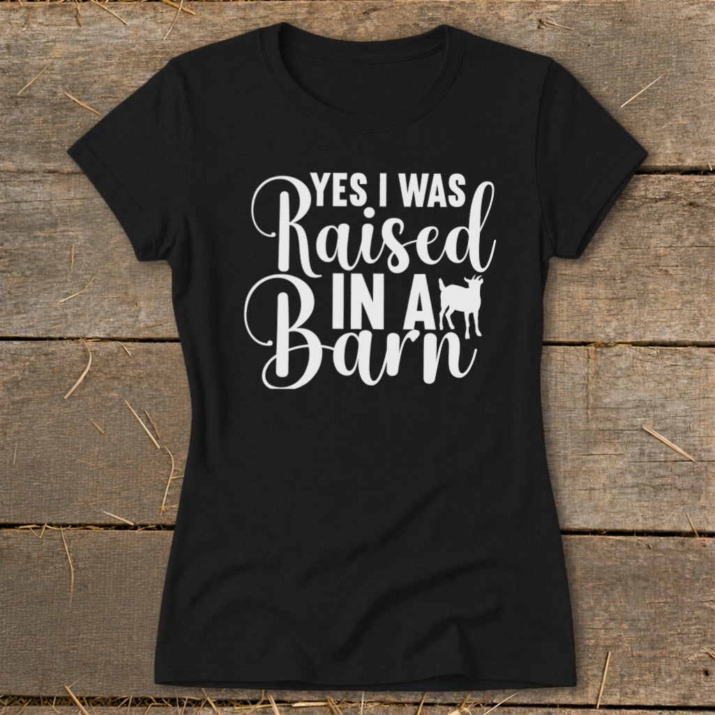 Black t-shirt with white text reading "YES I WAS Raised IN A Barn" and a goat silhouette.
