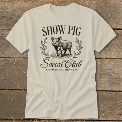 Light tan t-shirt with a vintage "Show Pig Social Club" graphic featuring a pig.