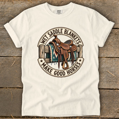 Cowboy saddle on a blanket over a fence with text "WET SADDLE BLANKETS MAKE GOOD HORSES".
