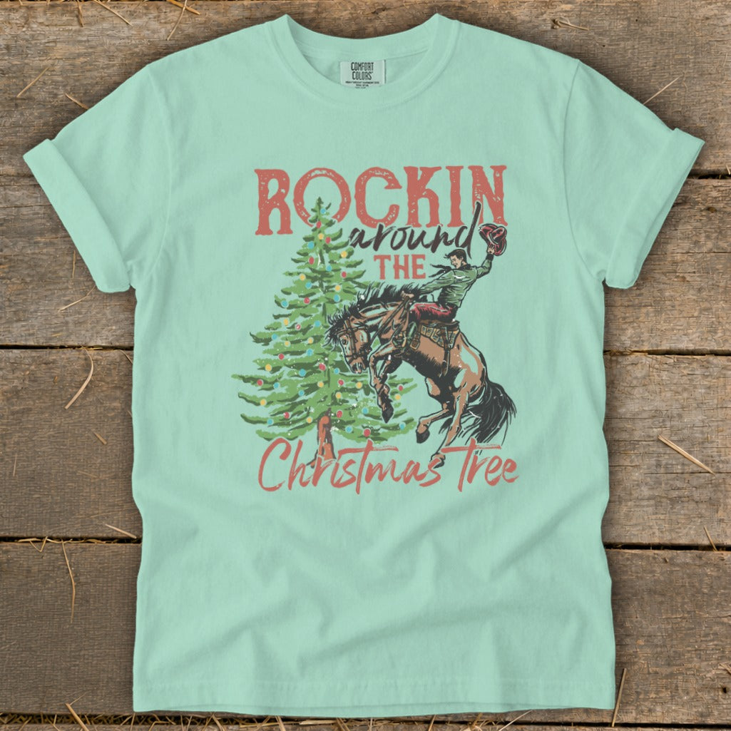 Light green t-shirt with "Rockin Around The Christmas Tree" graphic and bucking bronco rider.