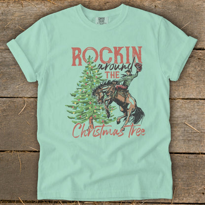 Light green t-shirt with "Rockin Around The Christmas Tree" graphic and bucking bronco rider.