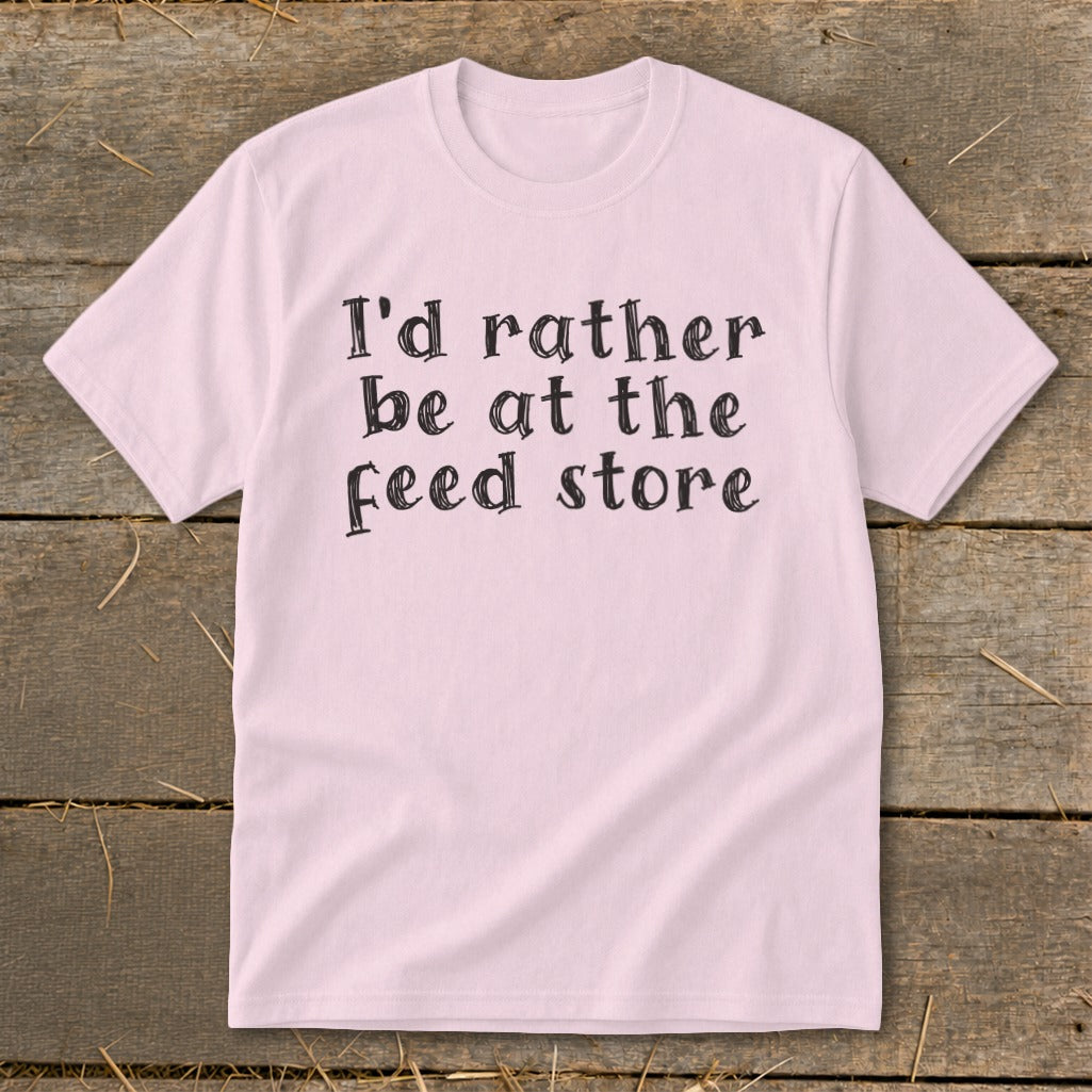 Pink t-shirt with black text that reads "I'd rather be at the feed store".