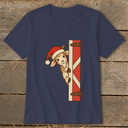 Goat wearing Santa hat peeks around a red barn door on navy t-shirt.