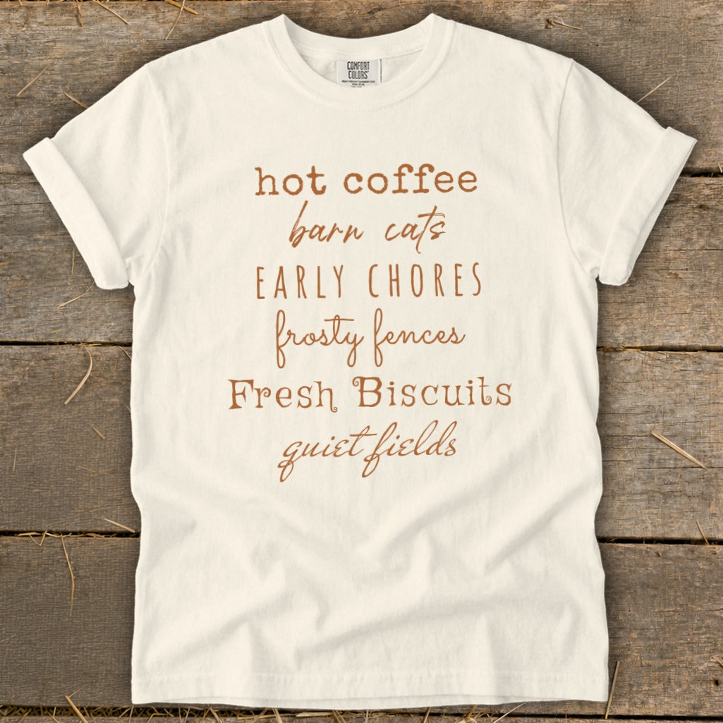 White t-shirt with brown text: hot coffee, barn cats, early chores, frosty fences, Fresh Biscuits, quiet fields.