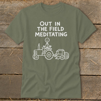 Green t-shirt with white text "OUT IN THE FIELD MEDITATING" and a stick figure meditating on a tractor.