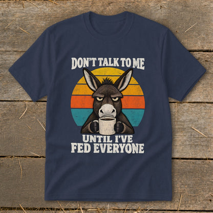 Navy blue t-shirt featuring an angry donkey holding a coffee mug, with retro sunset stripes and text.