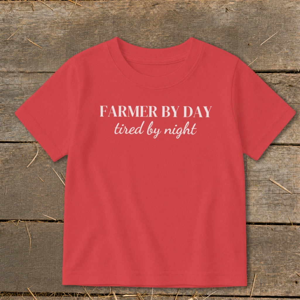 Red toddler t-shirt with "FARMER BY DAY tired by night" white text.