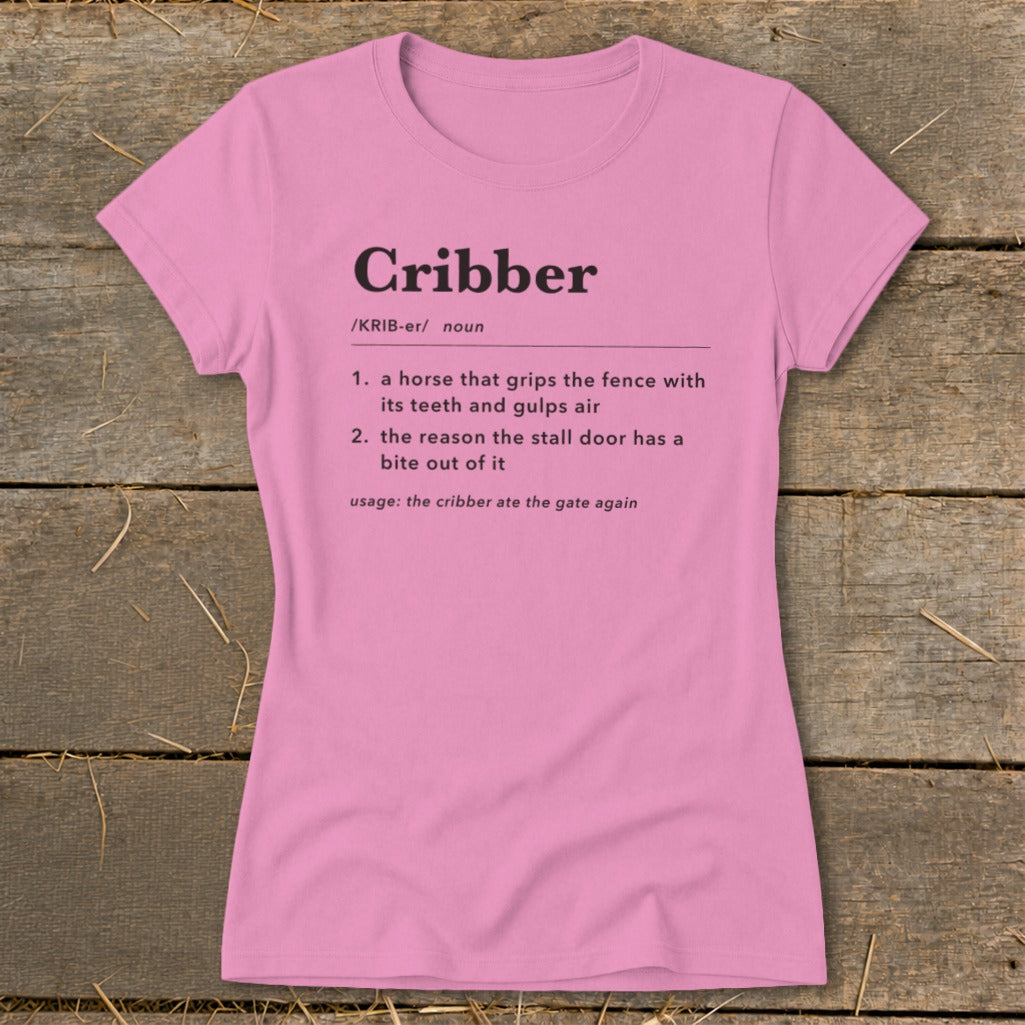 A pink women's t-shirt printed with a dictionary definition of the word cribber.