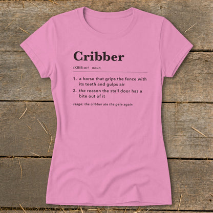 A pink women's t-shirt printed with a dictionary definition of the word cribber.