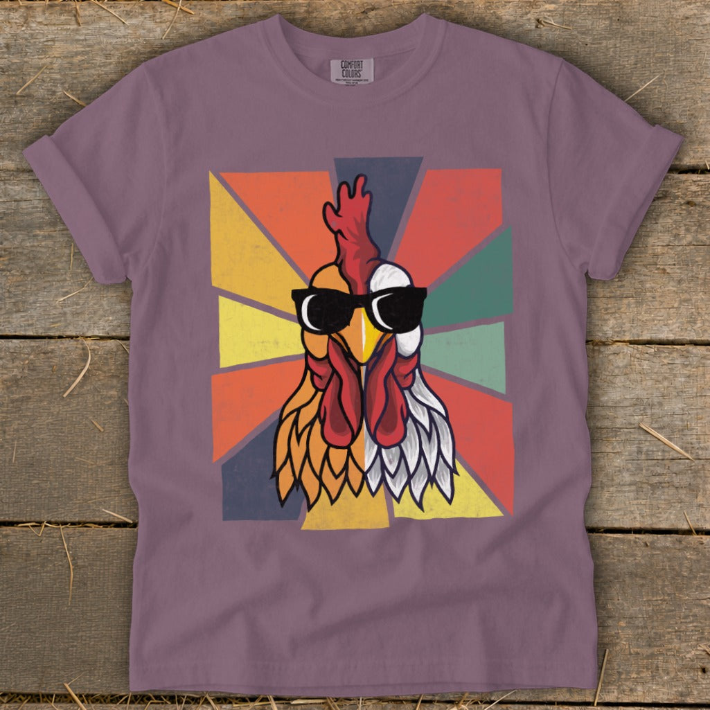 Retro rooster graphic with sunglasses on a purple t-shirt with a sunburst background.