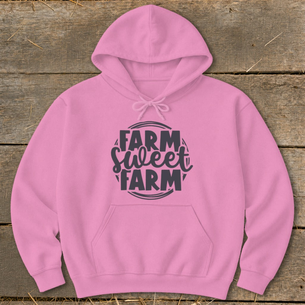 Pink hoodie with "FARM Sweet FARM" text graphic on a wooden background.