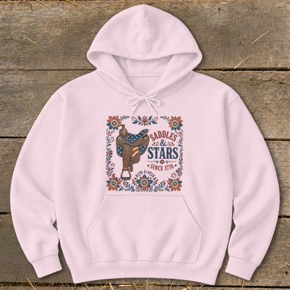 Pink hoodie with "Saddles & Stars Since 1776" text and western saddle graphic.