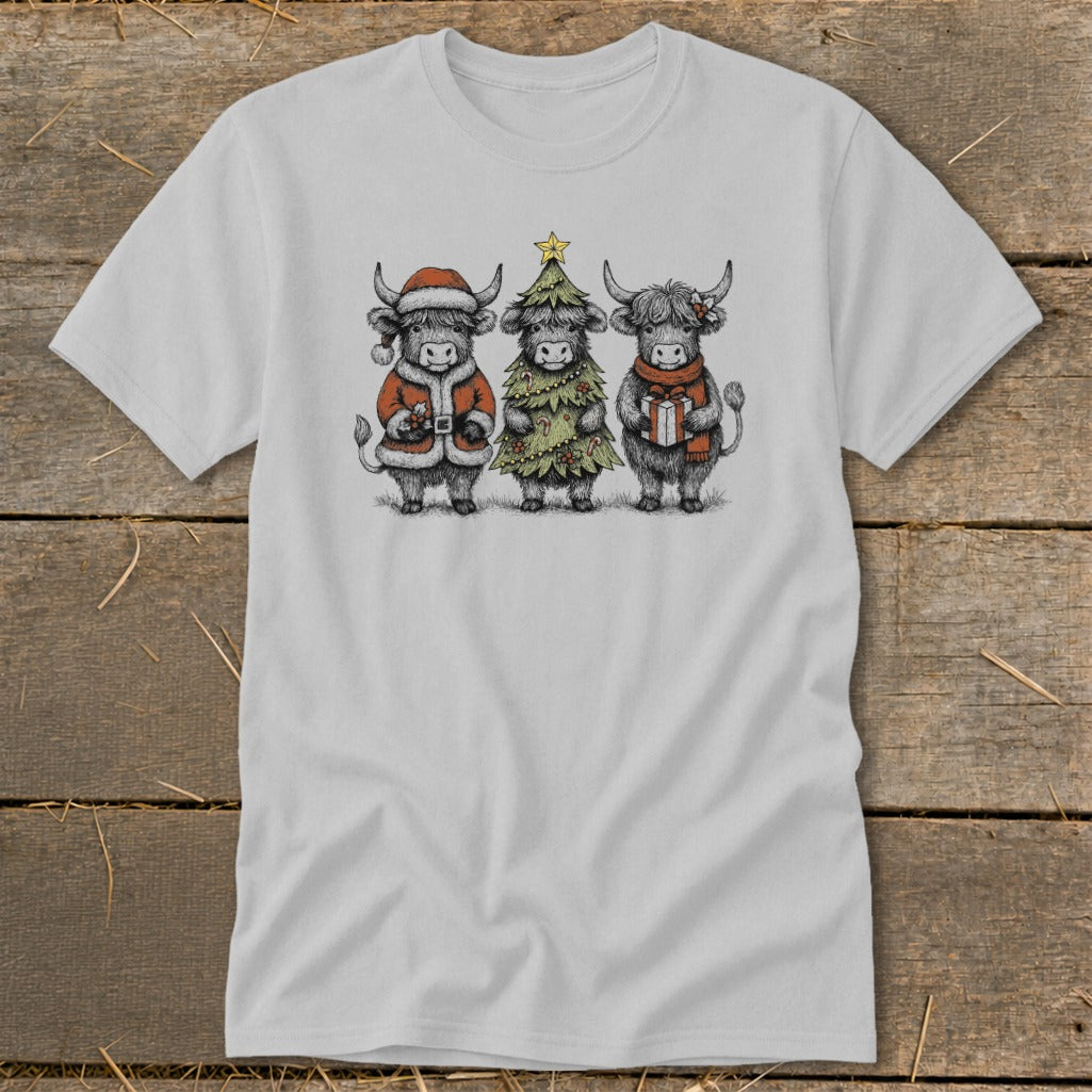 Three highland cows in festive attire, one dressed as Santa, one as a Christmas tree, one holding a gift.