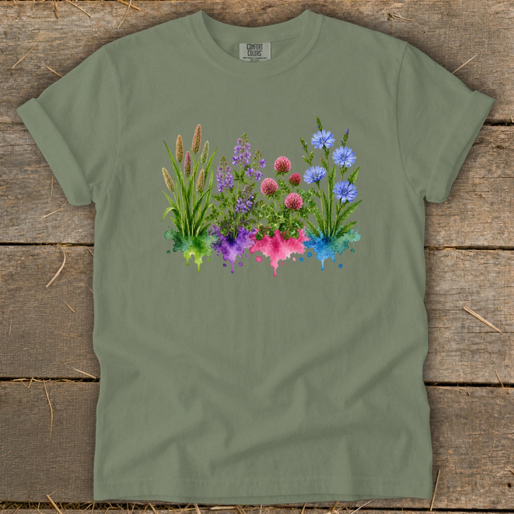 Sage green t-shirt featuring a watercolor graphic of four colorful wildflowers above matching paint splatters.