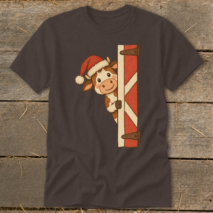 Brown t-shirt with a cartoon cow wearing a Santa hat peeking from behind a red barn door.