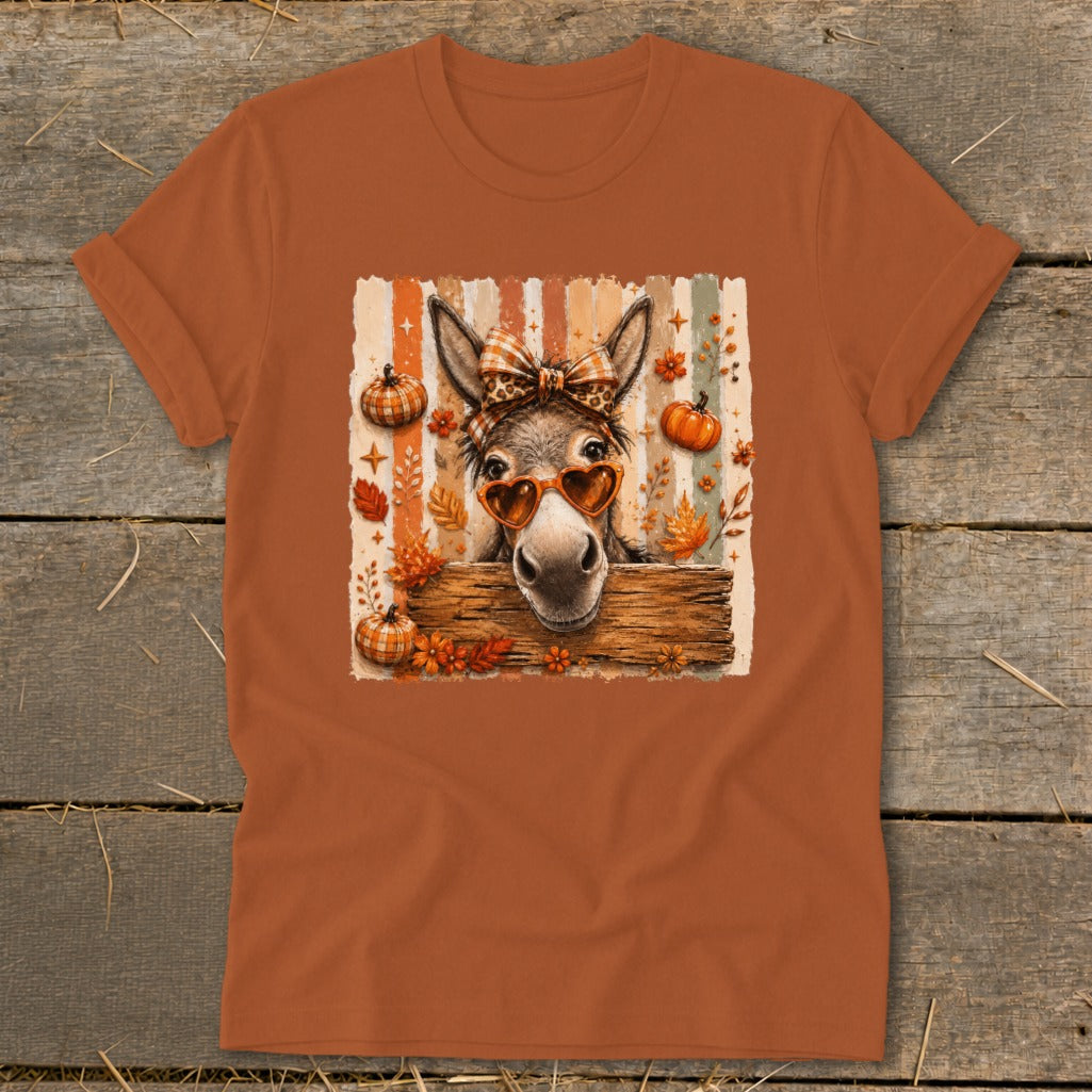 Donkey with heart sunglasses and bow on striped background with pumpkins and leaves.