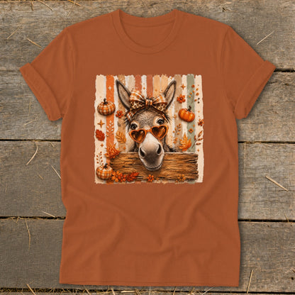 Donkey with heart sunglasses and bow on striped background with pumpkins and leaves.