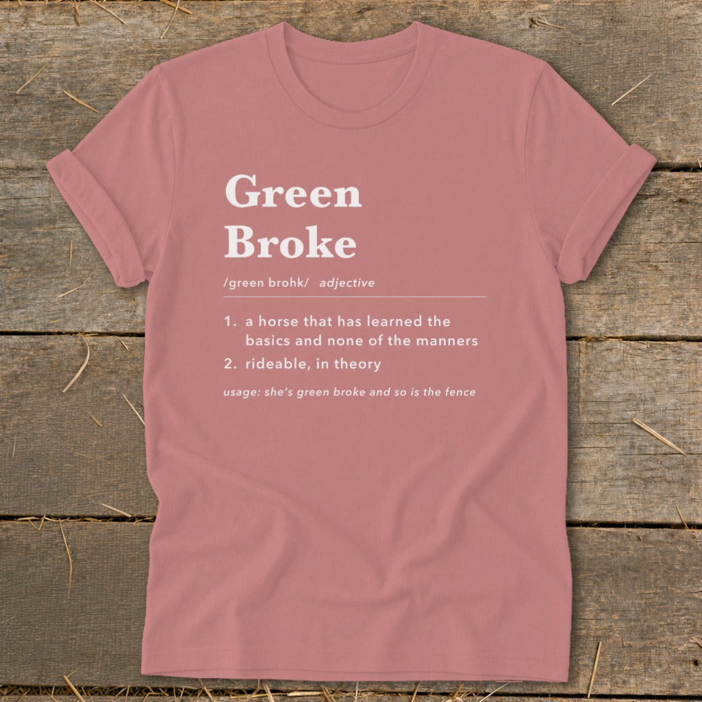 Dusty pink t-shirt with white dictionary-style text defining Green Broke laid on a wooden background.