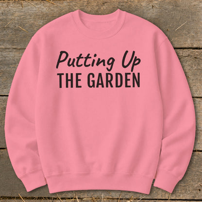 Pink sweatshirt with black text reading "Putting Up THE GARDEN".