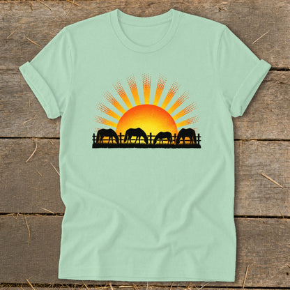 Mint t-shirt with horses grazing at sunrise graphic.