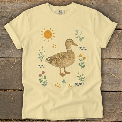 T-shirt with a duck illustration surrounded by flowers, sun, and water.