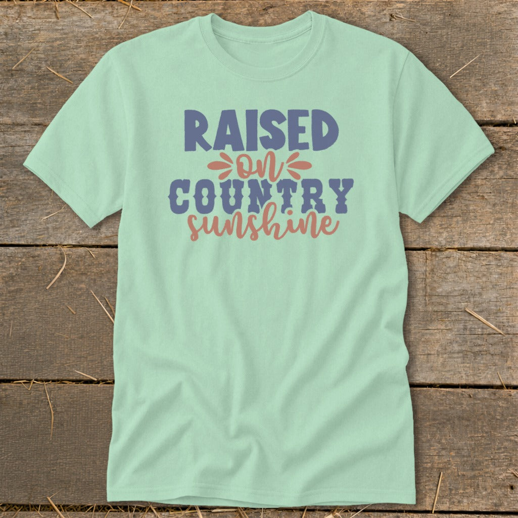 Light mint t-shirt with "Raised on Country Sunshine" text in blue and pink.