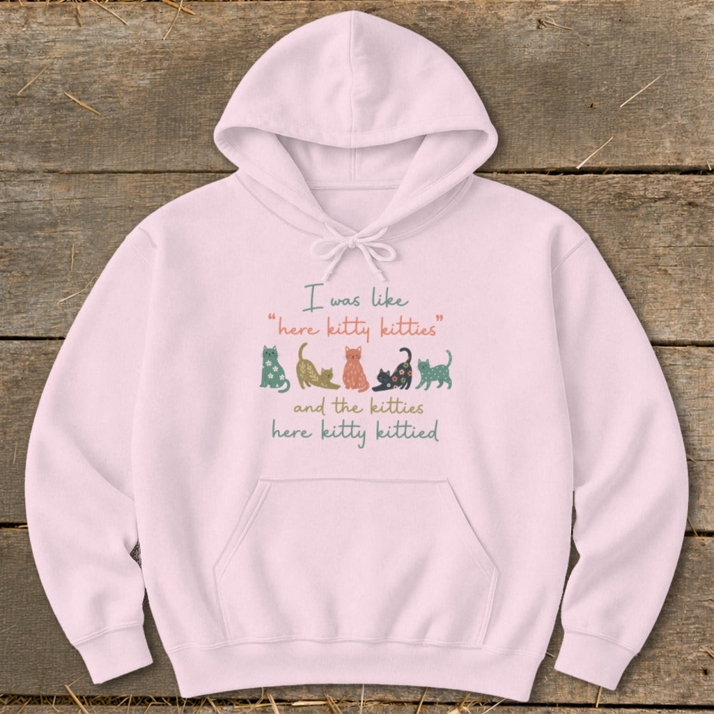 Pink hoodie with text "I was like 'here kitty kitties' and the kitties here kitty kittied" and cat illustrations.